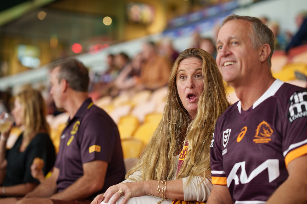 A woman sitting with a man and looking surprised at Suncorp Stadium.