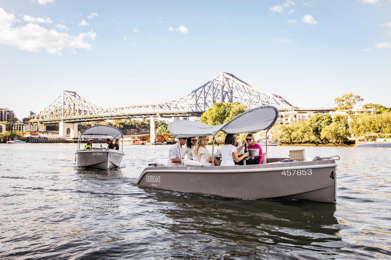 An image of two boats driving on the river towards the Story Bridge.