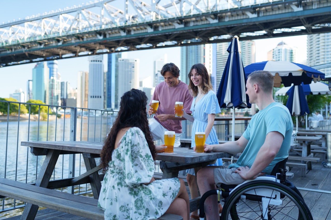A group of four people chatting and drinking near the water.