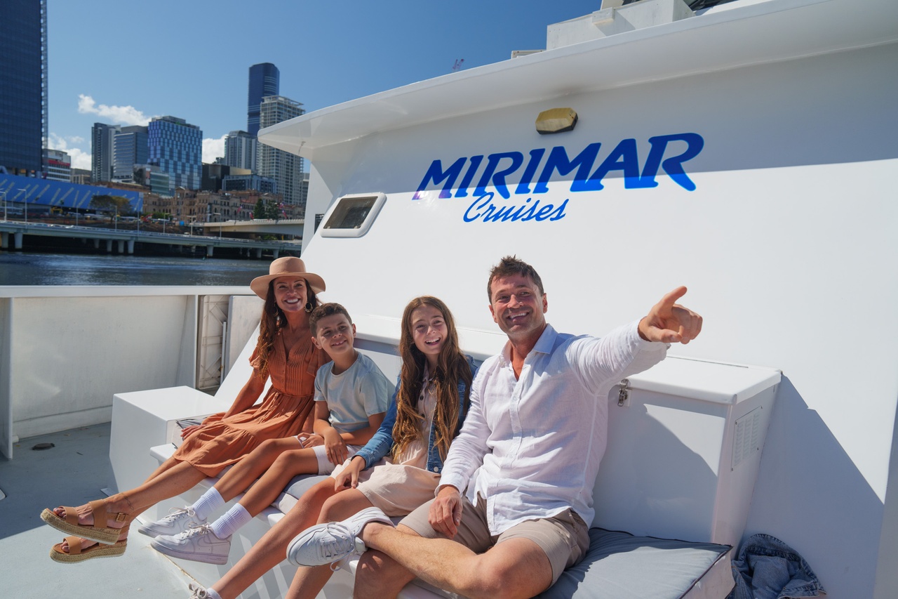 A family of four sitting on a  Mirimar Cruises boat and pointing out at the water.