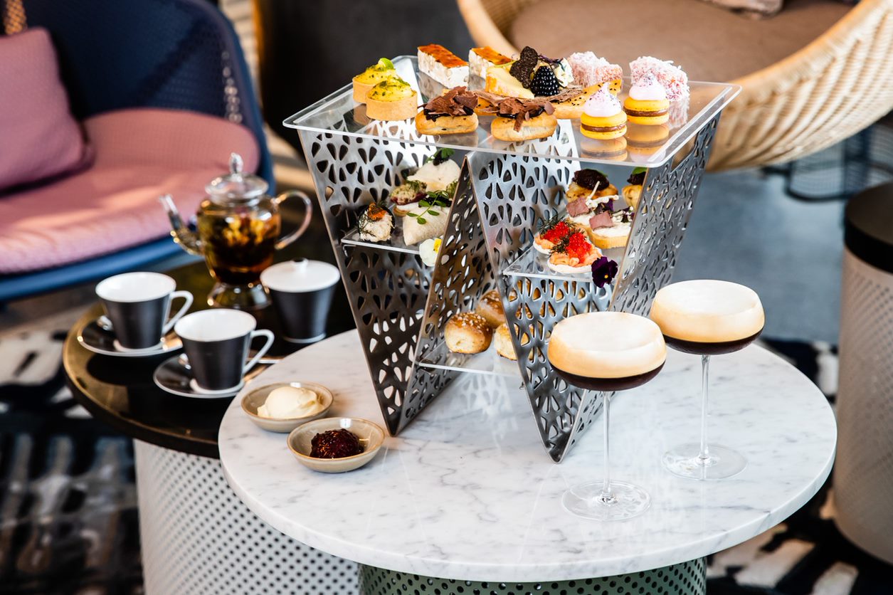 A portrait image of high tea set with Espresso Martini on the table