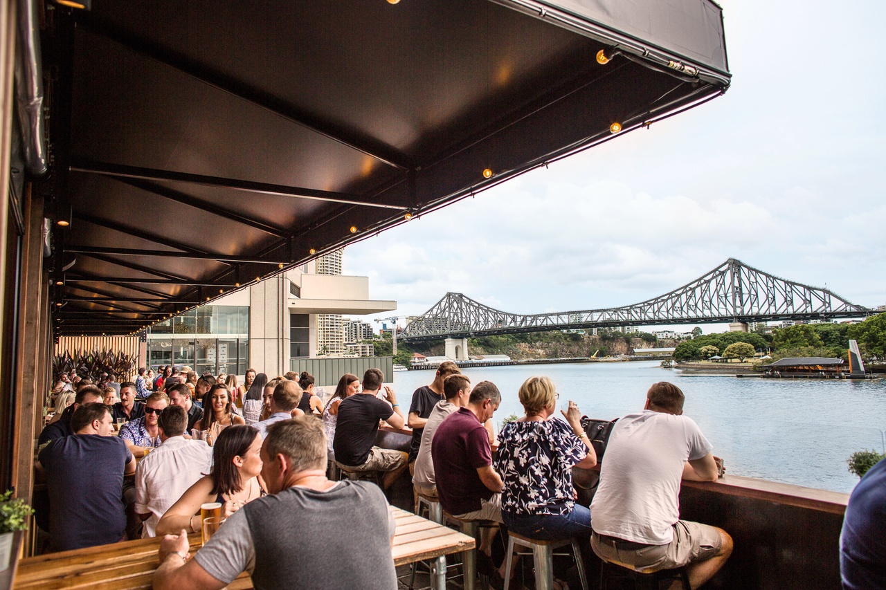 Crowded waterfront bar at Riverland with Story Bridge in backdrop.