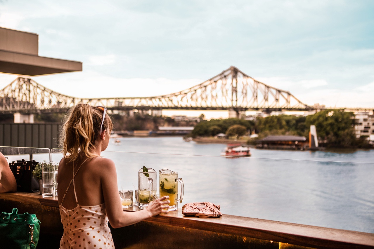 Girl having cocktails at Riverland looking toward the Story bridge