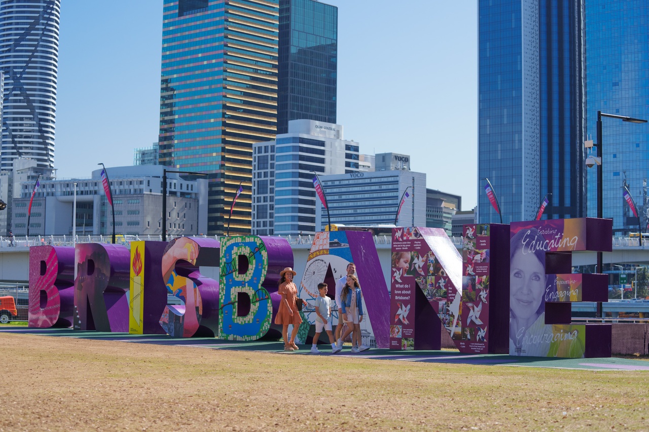 A family of four walking past the Brisbane sign.