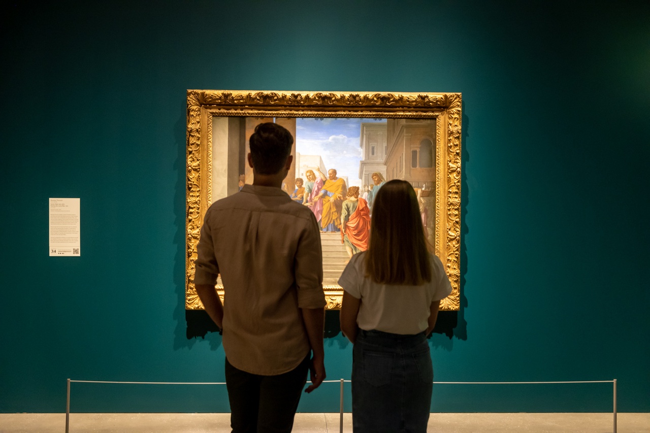 A couple are standing in front of a painting in an art gallery.