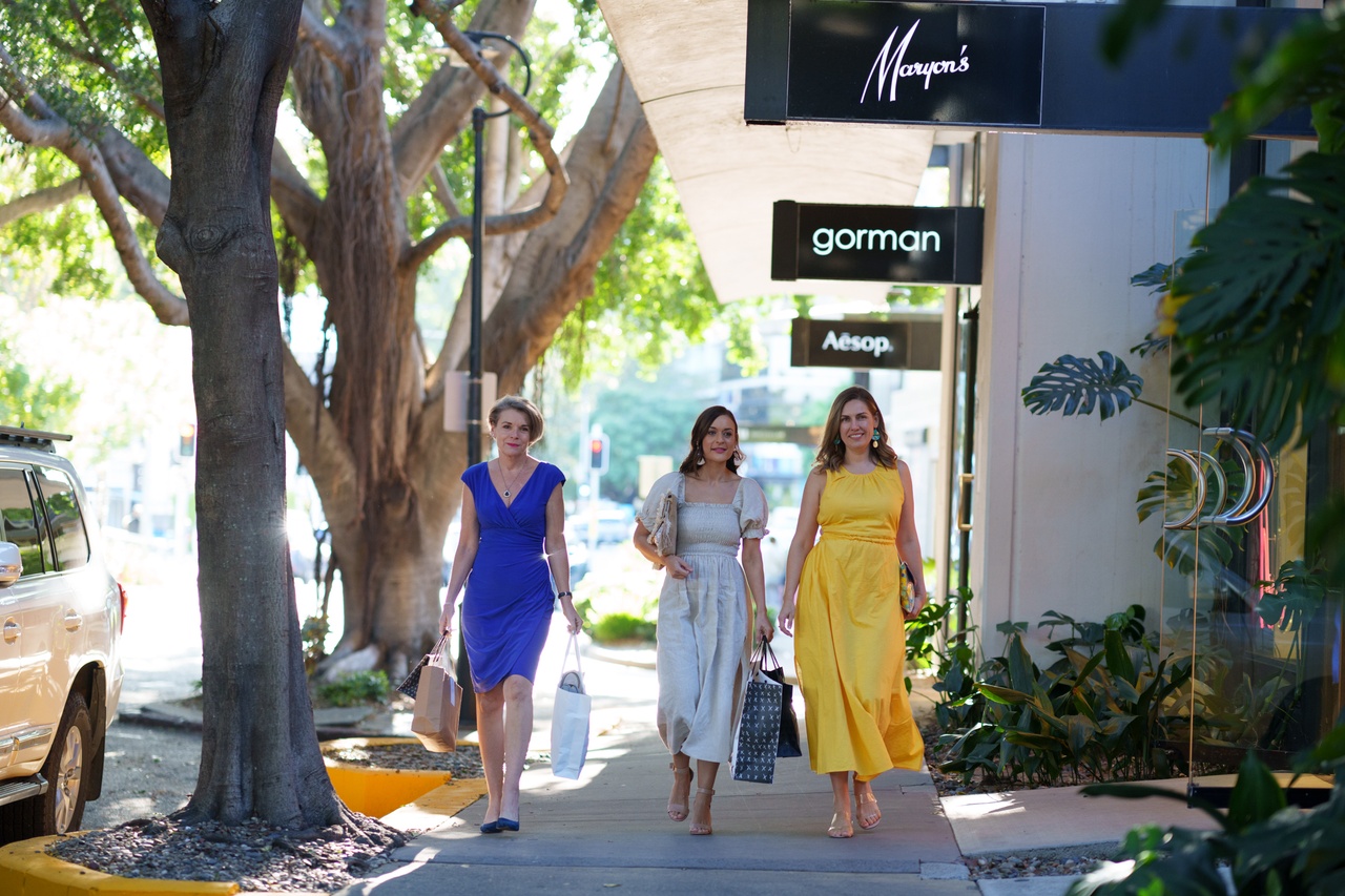 An image of three women walking past shops.
