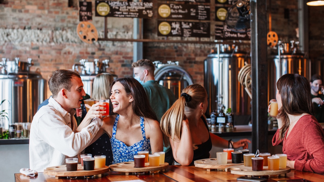 Couple laughing and sharing drinks at a beer tasting at Stone & Wood Brewing Co.