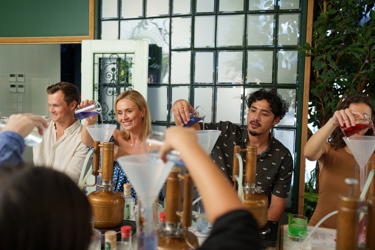 A group of five people pouring liquor into funnels at Brisbane Distillery.