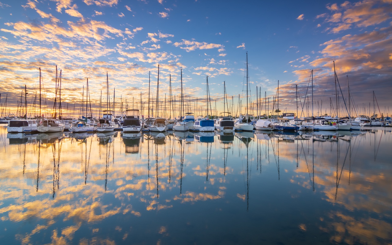The sun rises with boats in the foreground at Manly Marina.