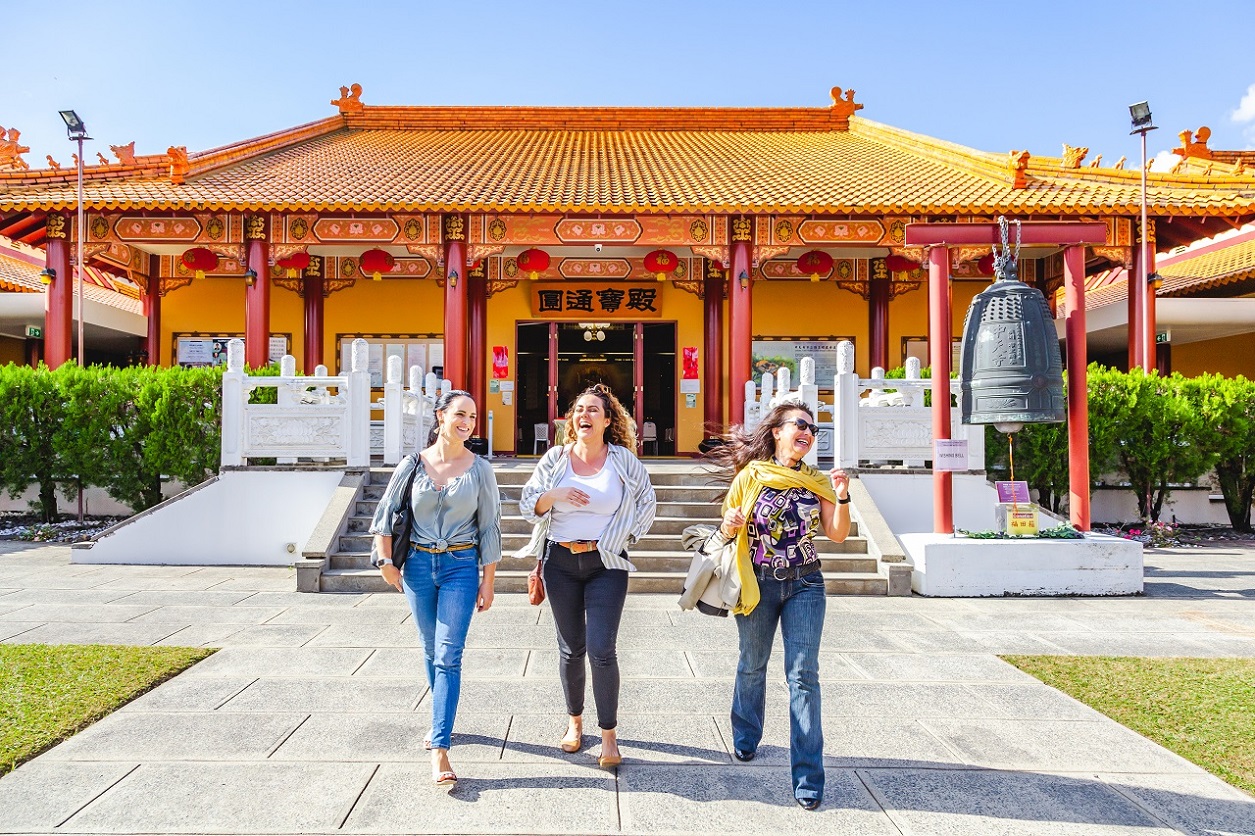 An image of three women laughing and walking in front of the temple main building.