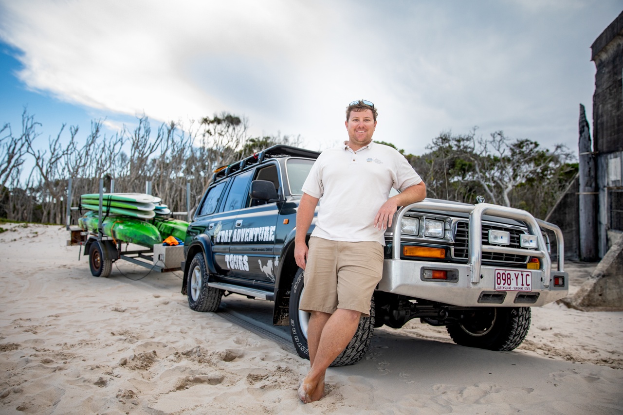An image of driver in front of 4WD on beach with G'Day Adventure Tours. 