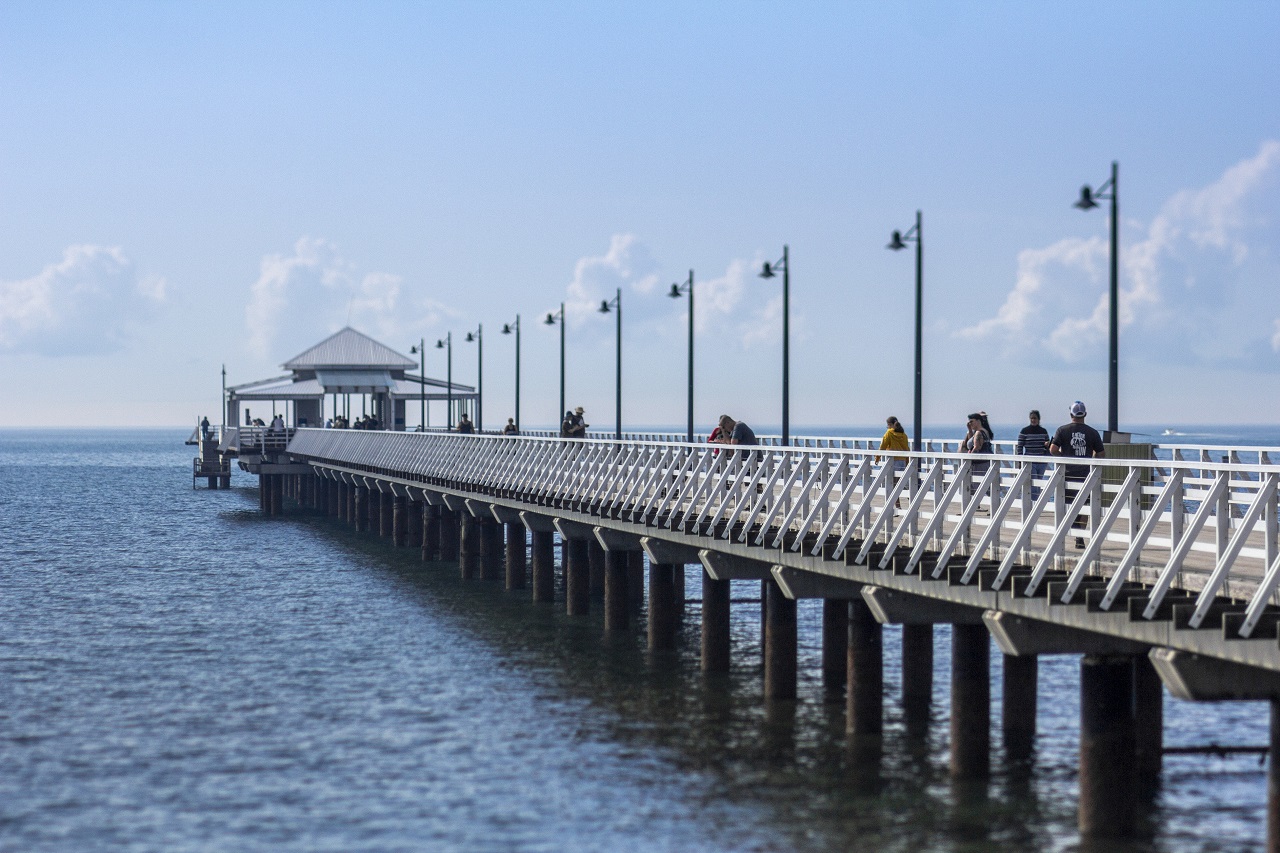 Small groups of people walking along Shorncliffe Pier.