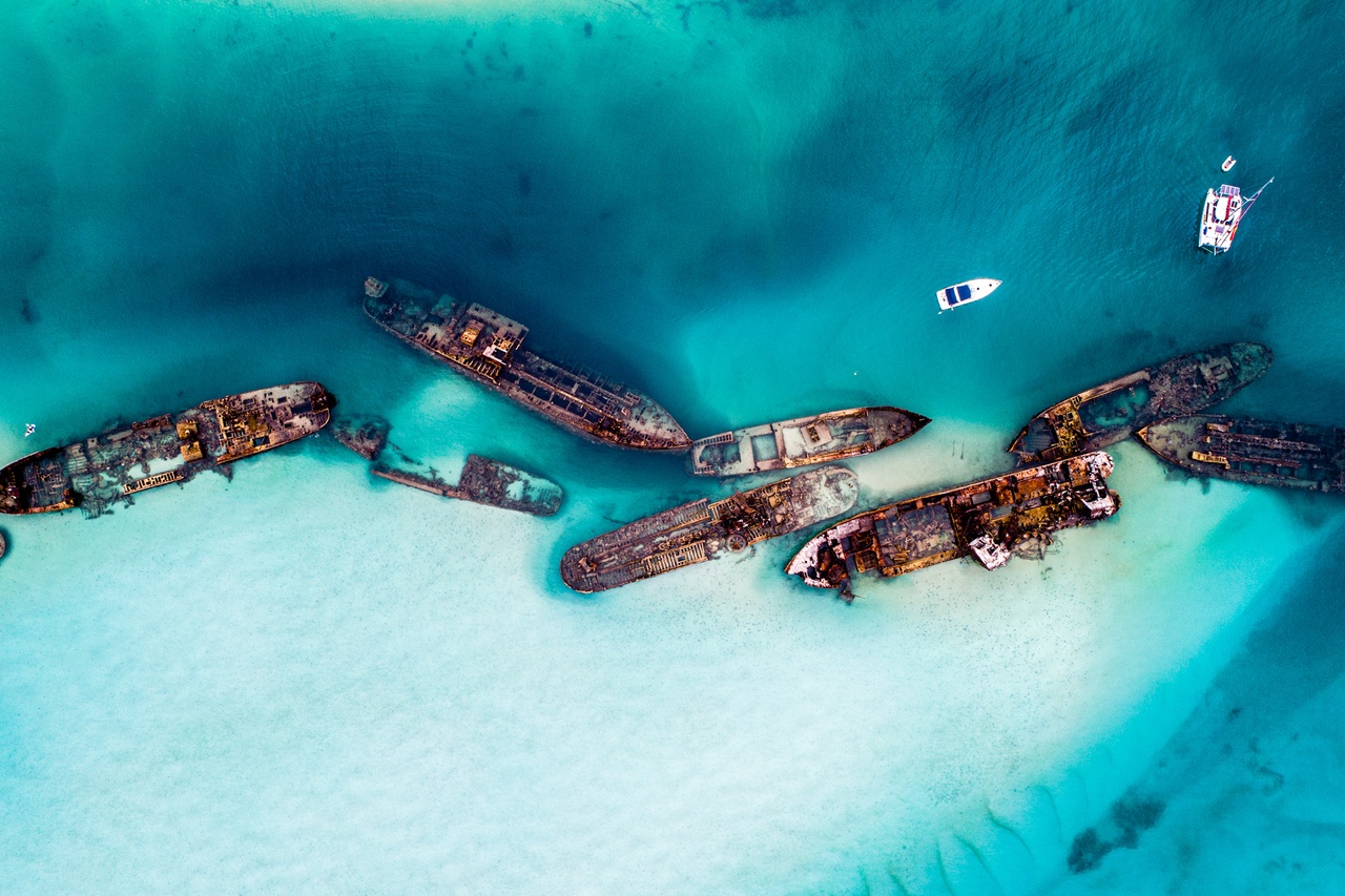 Aerial photos of the Tangalooma Wrecks, crystal blue water and boats anchored near the wrecks. 