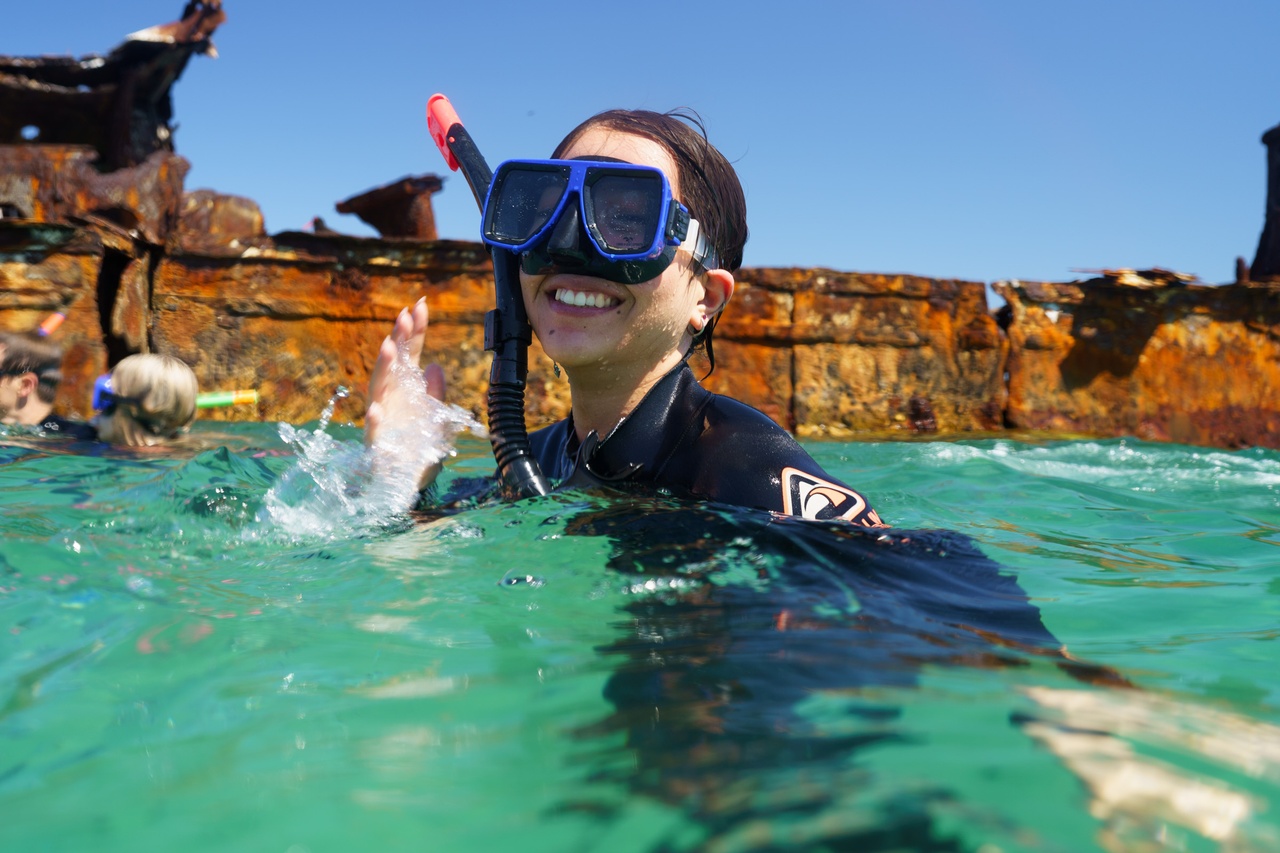 A close up of a woman smiling while snorkelling.
