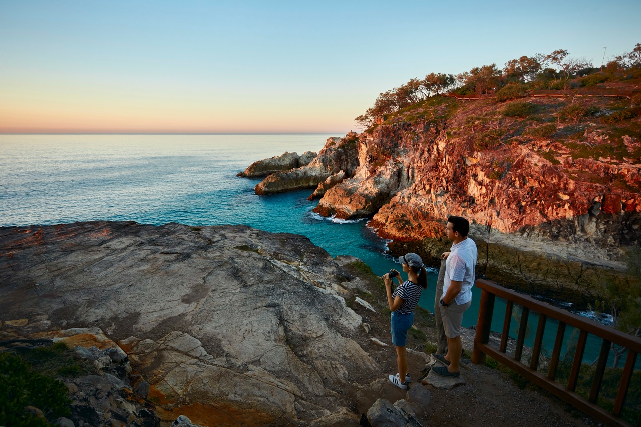 Landscape image of a couple watching sunset over the ocean at North Gorge walk on North Stradbroke Island/ Minjerribah.