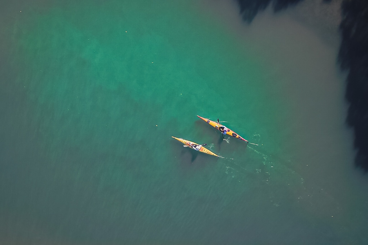 A directly above view of two kayaks on the green water sea