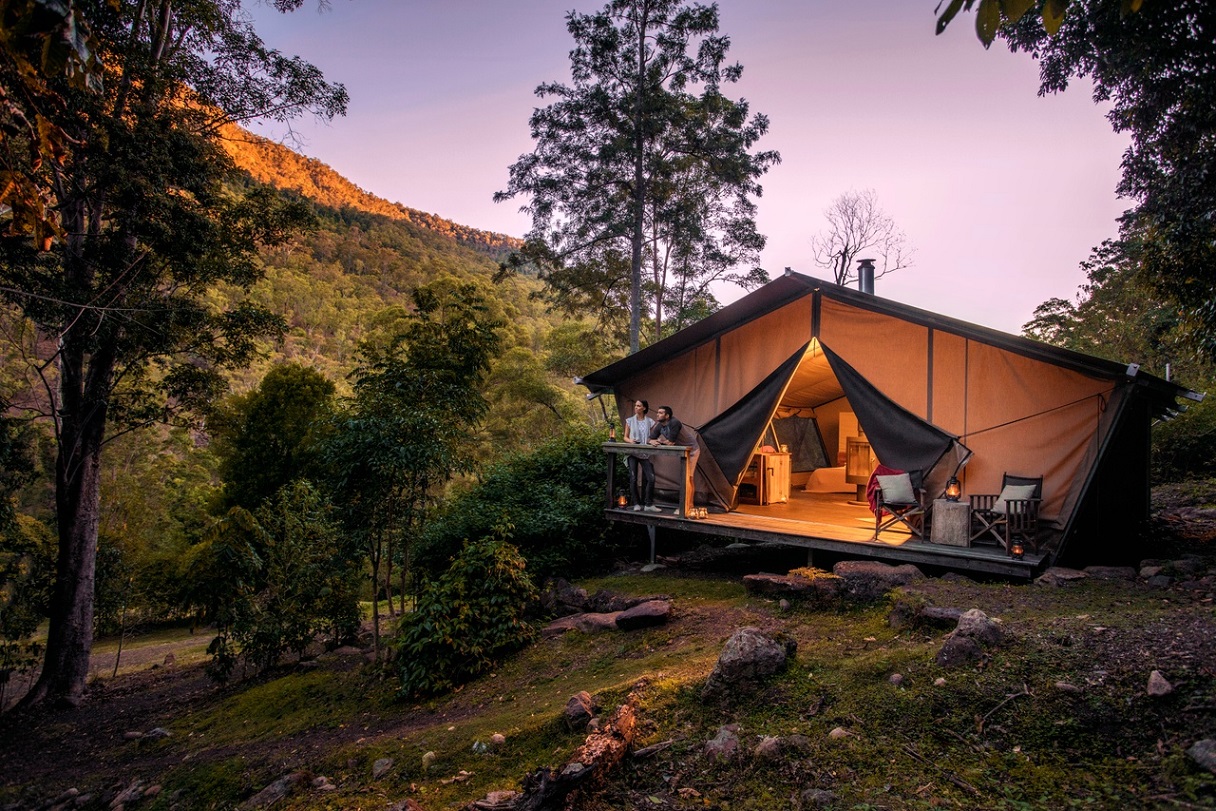 Couple standing in front of their glamping tent in the forest Nightfall Camp Scenic Rim