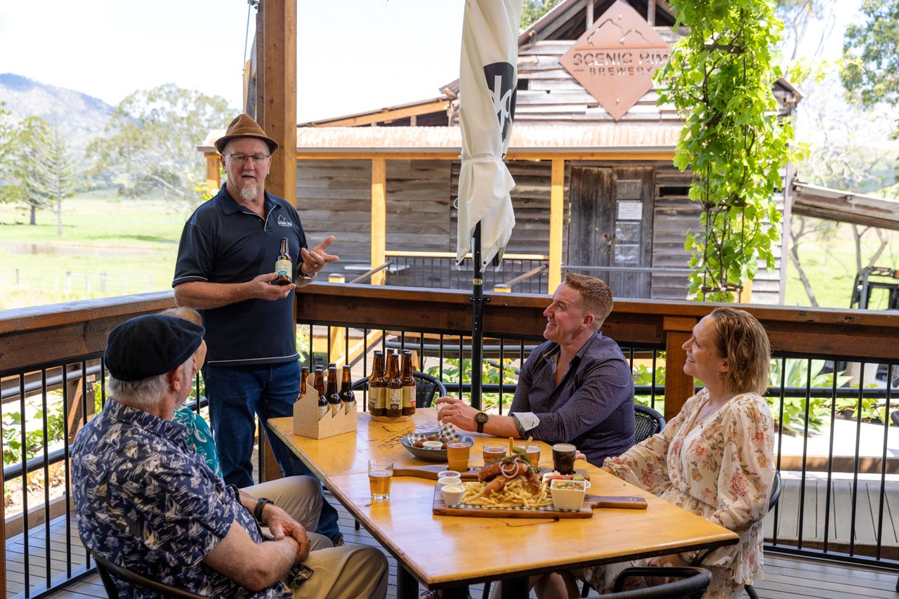 An image of a group of people at a restaurant, being shown a beer bottle by a male worker at Scenic Rim Brewery.