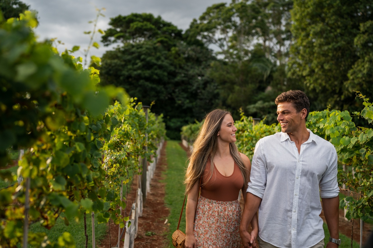 A couple walking and smiling in a vineyard at Witches Falls Winery.
